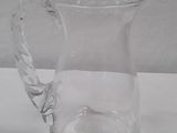 a clear glass pitcher with a handle on a table