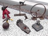 une statue représentant un homme avec une roue et d'autres objets posés au sol