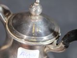 a silver tea pot with a label on it