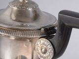 a silver tea pot with a black handle on a table
