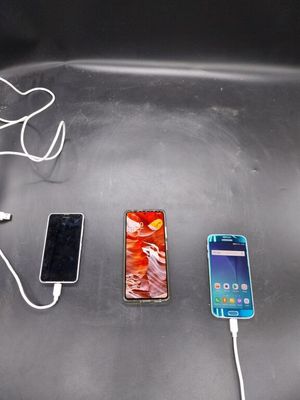 trois téléphones portables branchés sur un chargeur