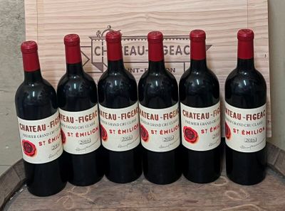 six bottles of red wine are lined up on a barrel