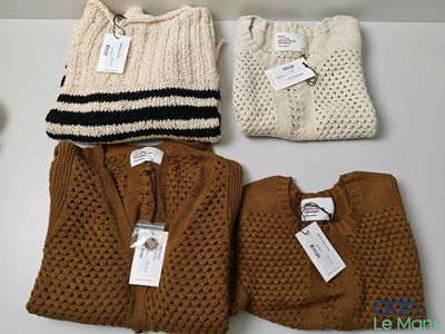 three pairs of sweaters and a hat are on a table
