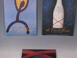 three posters on the wall of a room with a vase and a bottle of wine
