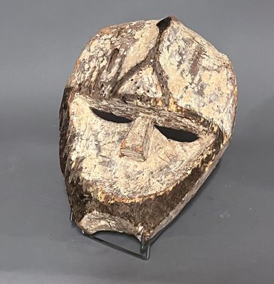 une image représentant un masque en bois posé sur un socle en métal