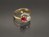 un gros plan d'une bague en or sertie d'une pierre rouge et blanche