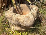 une jardinière en pierre posée au milieu de la pelouse