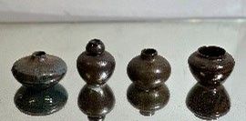 four vases sitting on a glass table with a white background