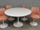 an image of a white table with four orange chairs around it