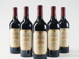 four bottles of red wine are lined up on a white surface