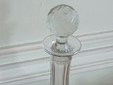 a glass decanter on a table with a white wall in the background