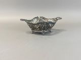 a close up of a silver bowl on a white surface
