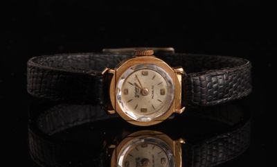 une image représentant une montre-bracelet dorée posée sur une surface noire