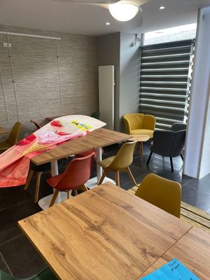 une table et des chaises dans une pièce, avec une fenêtre en arrière-plan