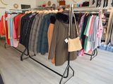 a rack of clothes in a clothing store with clothes hanging on it