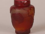 un vase rouge orné d'un motif de feuilles