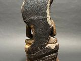 sculpture of a woman sitting on a rock on a wooden base