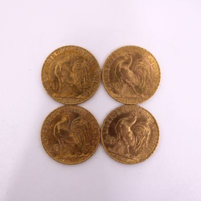 four gold coins sitting on top of each other on a white surface