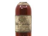 une vieille bouteille de whisky posée sur une surface blanche