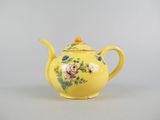 yellow teapot with flowers and leaves painted on it