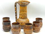 cinq tasses et un pichet posés les uns à côté des autres sur une table