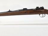 un fusil posé sur un socle en acrylique transparent, sur fond blanc