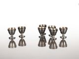 quatre tasses en argent posées les unes à côté des autres sur une table