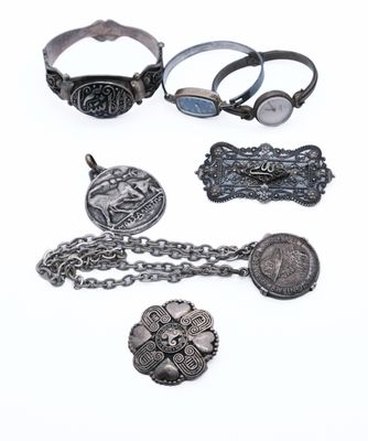 an assortment of silver jewelry on a white surface with a white background