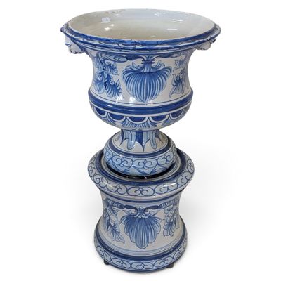 un grand vase bleu et blanc posé au sommet d'une pile de petits vases bleus et blancs