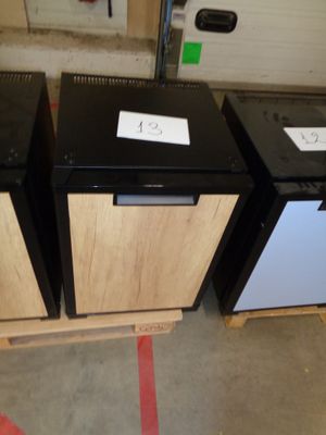 three black and white refrigerators sitting in a warehouse