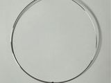 a close up of a silver necklace with a small silver object on it