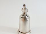 a silver bell with a bird on top of it
