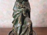 statue d'une femme tenant un bébé posé sur un plateau posé sur une table en bois