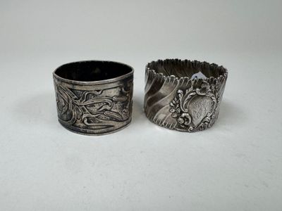 pair of antique silver napkins with designs on them on a white surface