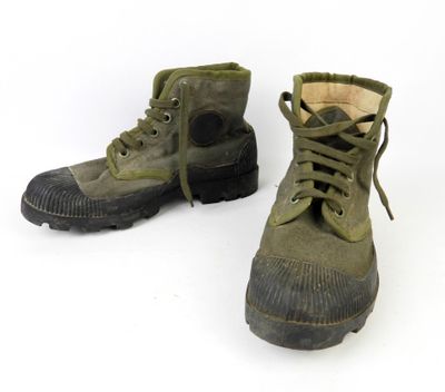 une paire de bottes vert militaire posées sur une surface blanche
