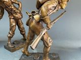 three bronze figurines of soldiers with guns and helmets