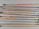 six wooden arrows are arranged in a row on a gray surface