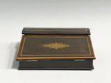 an old black and gold box sitting on top of a white table