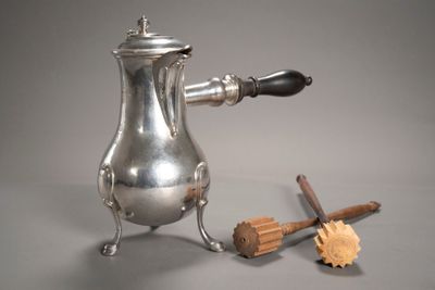 une cafetière en argent posée sur une table, à côté d'un morceau de bois
