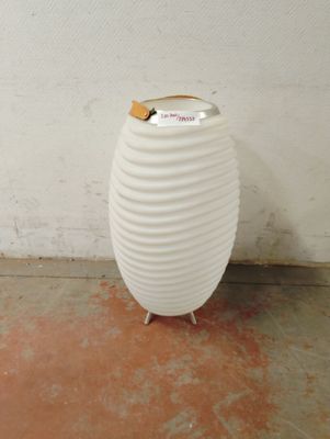 un grand vase blanc posé par terre dans une pièce