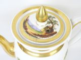 a tea pot with a golden handle on a white table