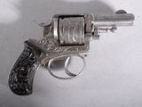 a silver revolver on a white surface with a shadow on the wall