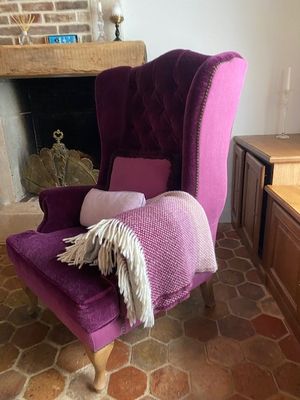 un fauteuil violet recouvert d'une couverture, placé devant une cheminée