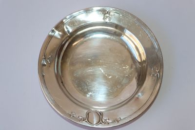 une assiette en argent posée sur une table, sur fond blanc