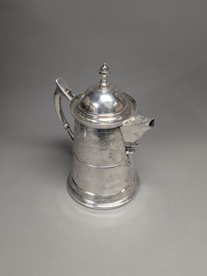 une cafetière ancienne en argent ornée d'un oiseau sur le couvercle
