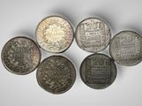 a group of five silver coins on a white surface