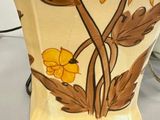a vase with a yellow flower on it sitting on a table