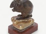 statue of a mouse sitting on a rock on a white background