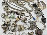 a pile of silver jewelry on a white surface