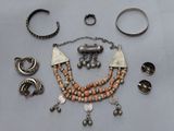 an assortment of silver and coral colored jewelry including rings, bracelets, and rings